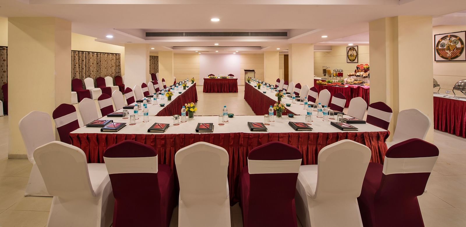 A brightly lit conference room is arranged with a long central table and numerous chairs set for a meeting - Lords Inn Vadodara