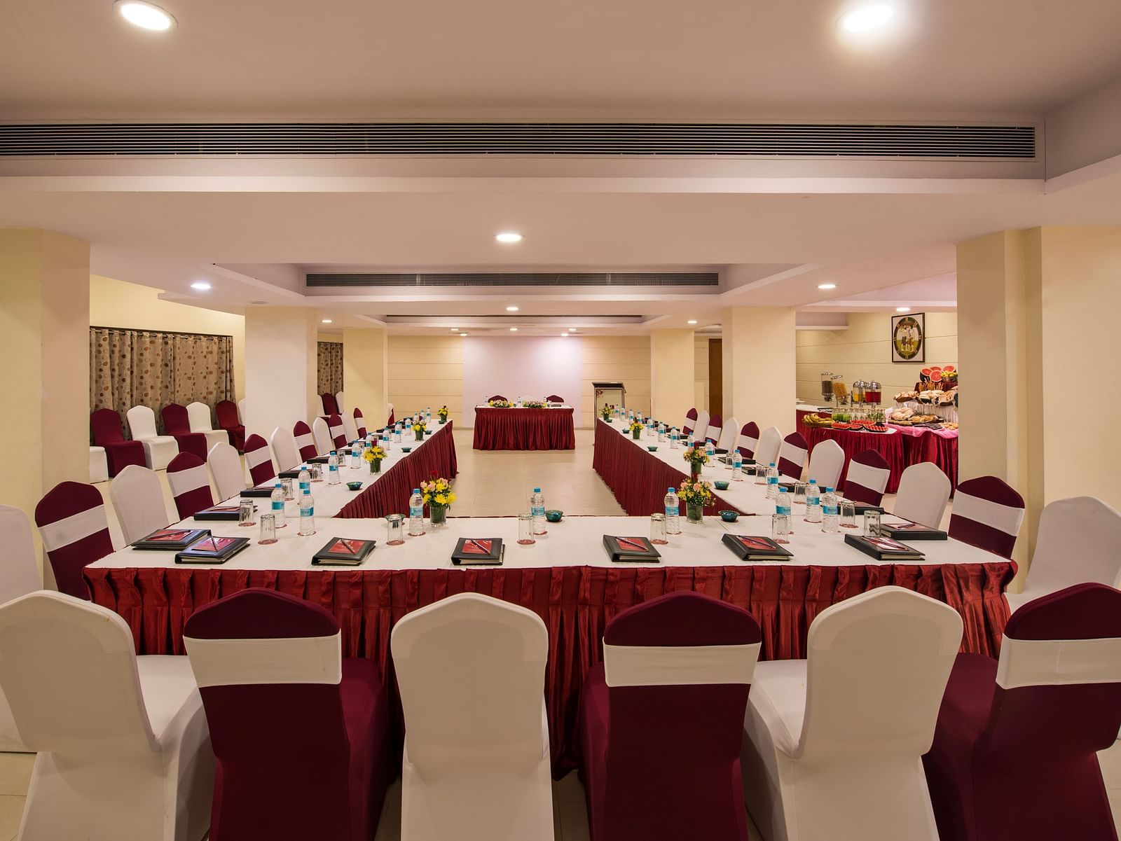 A brightly lit conference room is arranged with a long central table and numerous chairs set for a meeting - Lords Inn Vadodara