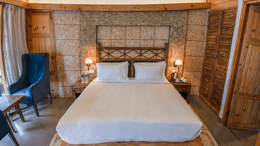 A large bed placed next to chairs at Superior Room at the Sylvan Retreat, Dehradun.