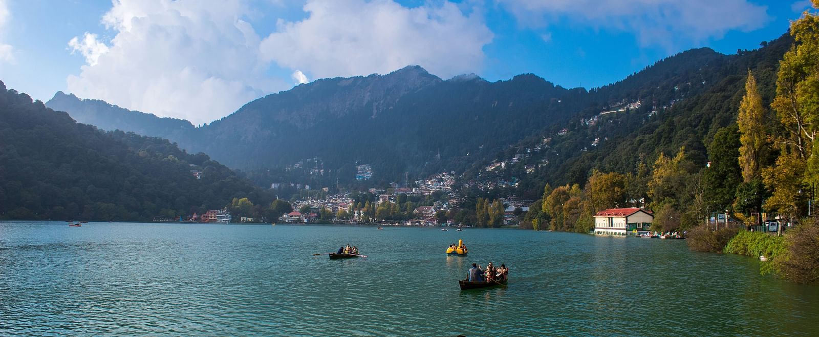 Serene lake views with boats and mist-covered hills in the background.