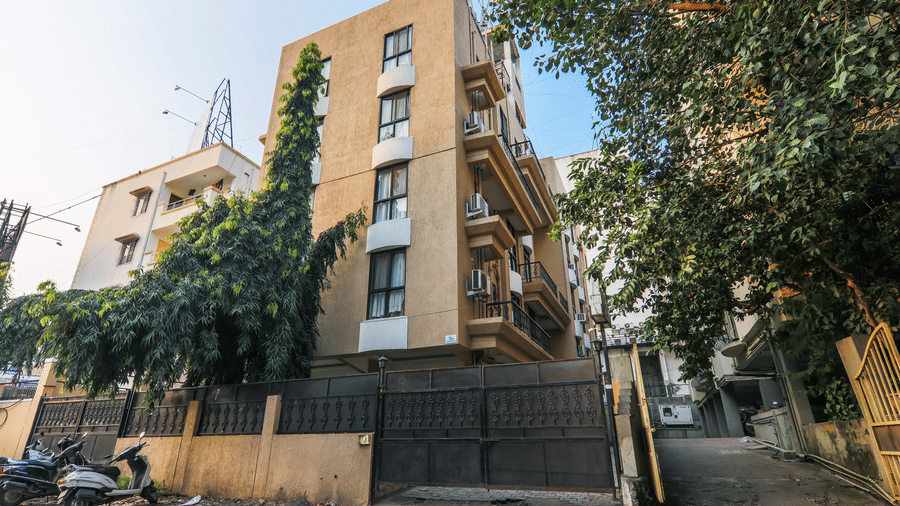 An apartment-style building with entrance gate, parked scooters, and surrounding trees | Calypso exterior