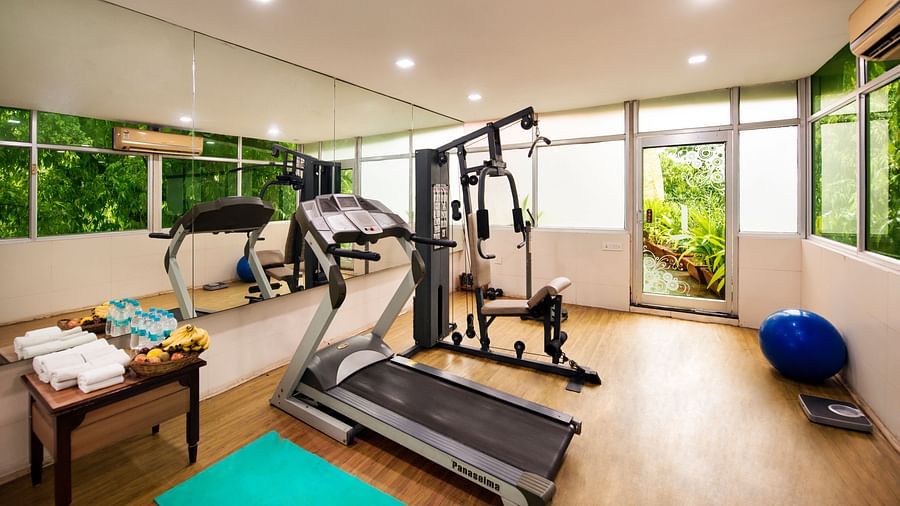 A well-equipped hotel gym features treadmills, weight machines, exercise balls, and a green yoga mat - Lords Inn Vadodara