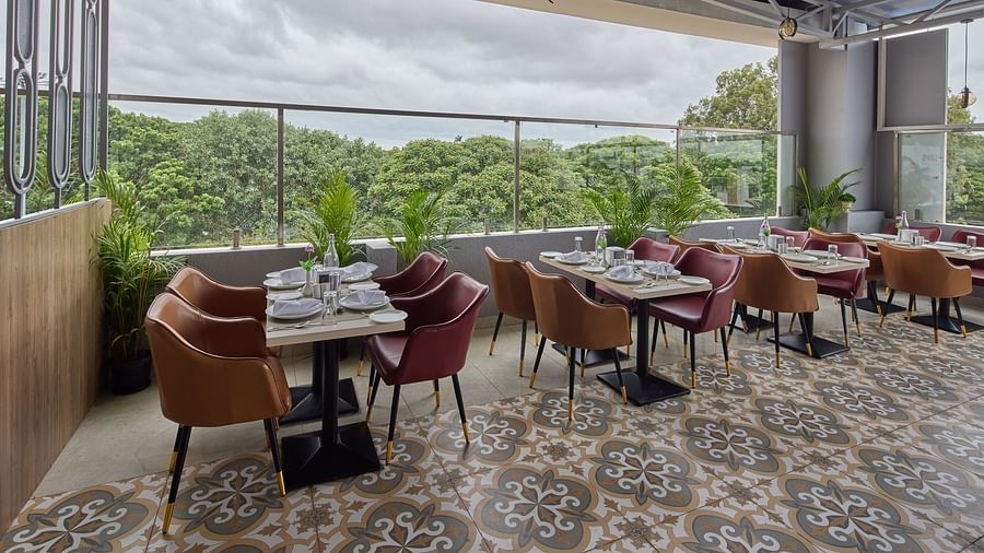 A restaurant with cosy tables, chairs and a view of the surrounding veranda