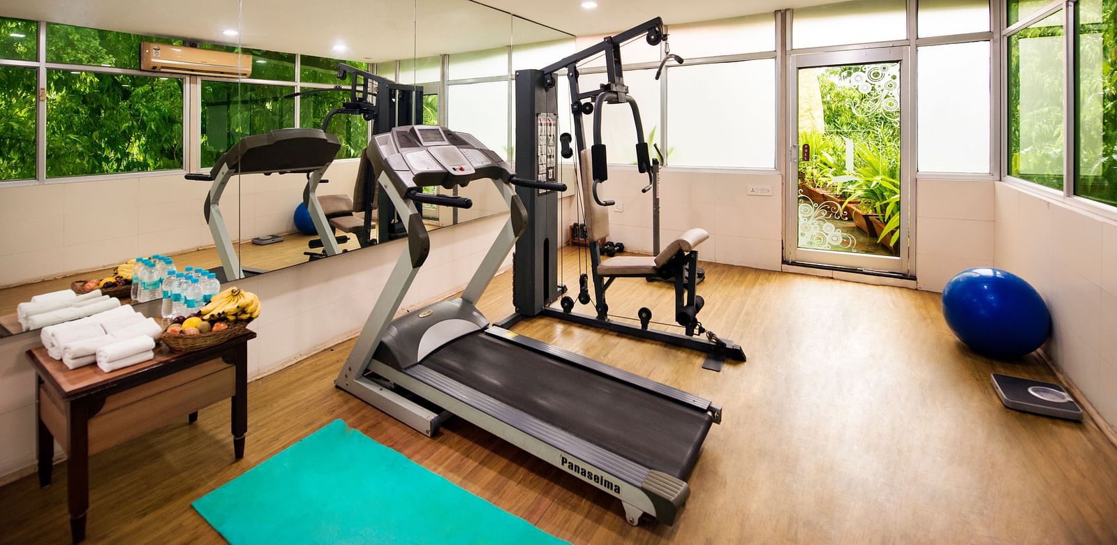 A well-equipped hotel gym features treadmills, weight machines, exercise balls, and a green yoga mat - Lords Inn Vadodara