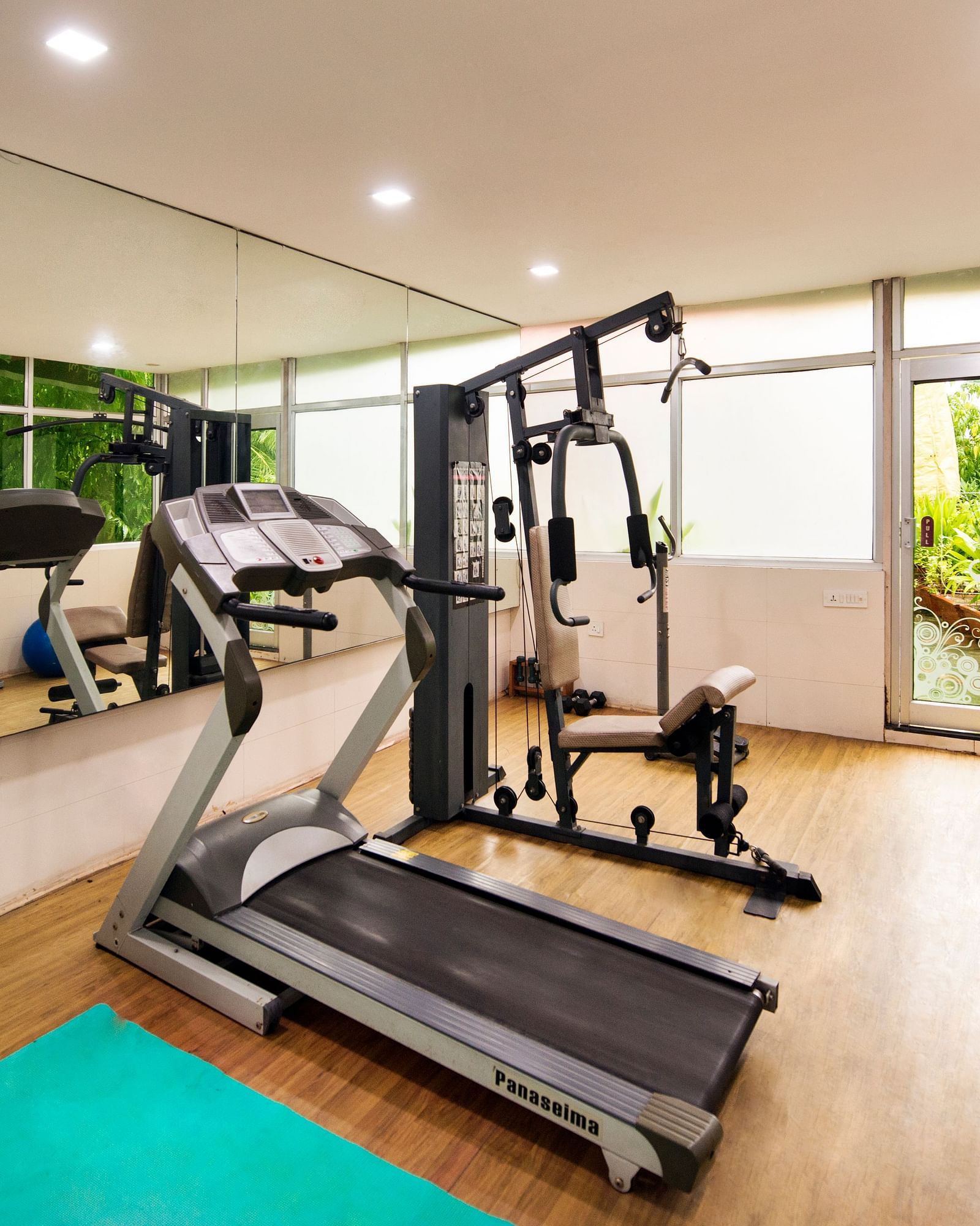 A well-equipped hotel gym features treadmills, weight machines, exercise balls, and a green yoga mat - Lords Inn Vadodara