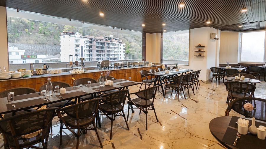 Image a dining space with chairs and tables and view of the surrounding area at Stone Wood Hotel, Rishikesh. 