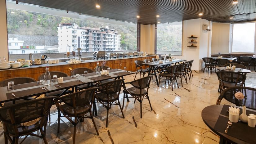 Image a dining space with chairs and tables and view of the surrounding area at Stone Wood Hotel, Rishikesh. 