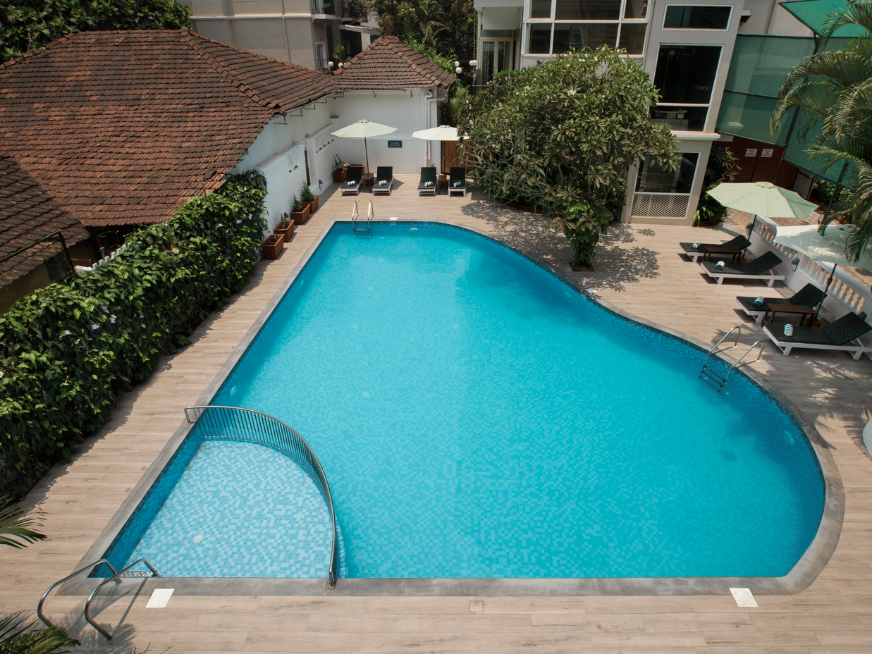 Outdoor swimming pool with sun loungers at Ocean Palms Hotel Goa