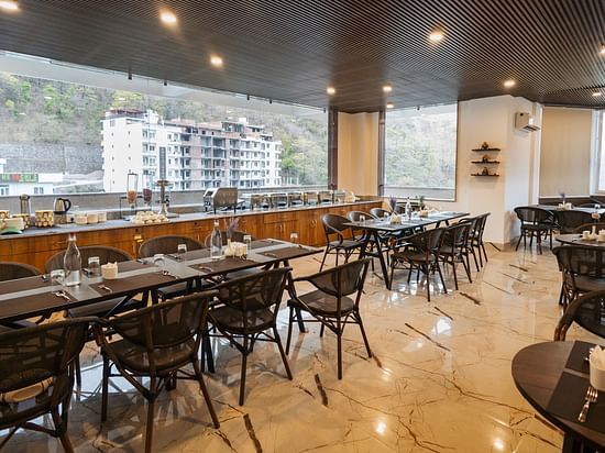 Image a dining space with chairs and tables and view of the surrounding area at Stone Wood Hotel, Rishikesh. 