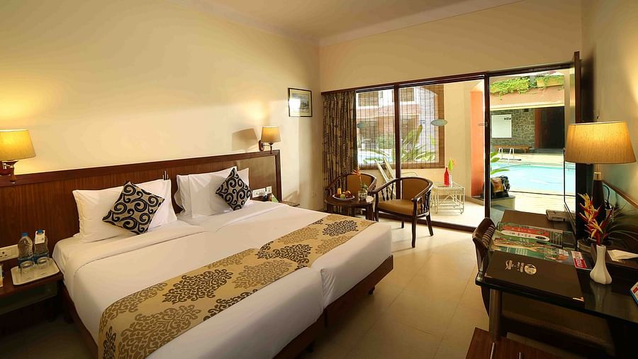 The Standard Room at Uday Samudra Leisure Beach Hotel, Kovalam, includes twin beds, a seating area, a desk, and a pool-view balcony.