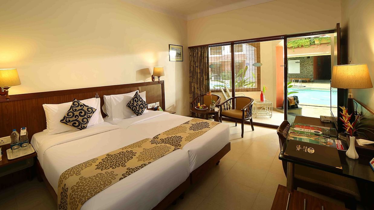 The Standard Room at Uday Samudra Leisure Beach Hotel, Kovalam, includes twin beds, a seating area, a desk, and a pool-view balcony.
