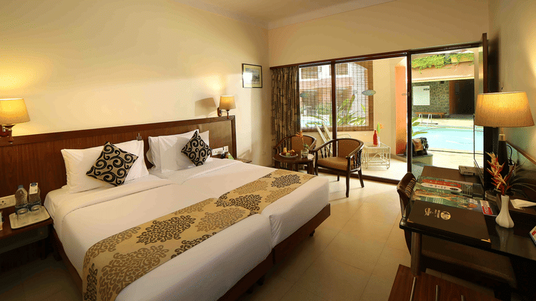 The Standard Room at Uday Samudra Leisure Beach Hotel, Kovalam, includes twin beds, a seating area, a desk, and a pool-view balcony.