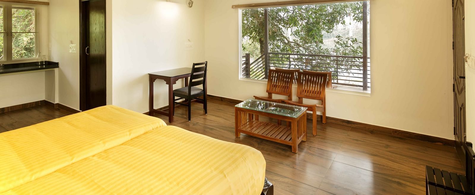 A bedroom with a bed, a desk, and a view of the outside.