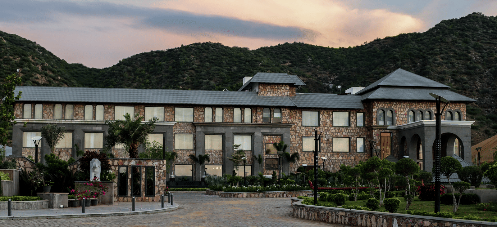 A different angle of the main resort building, with the driveway in the foreground and a warm, sunset-coloured sky.