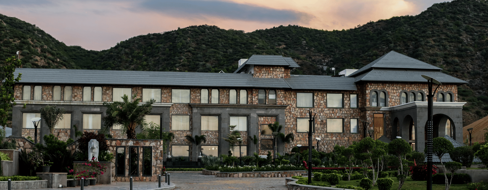 A different angle of the main resort building, with the driveway in the foreground and a warm, sunset-coloured sky.