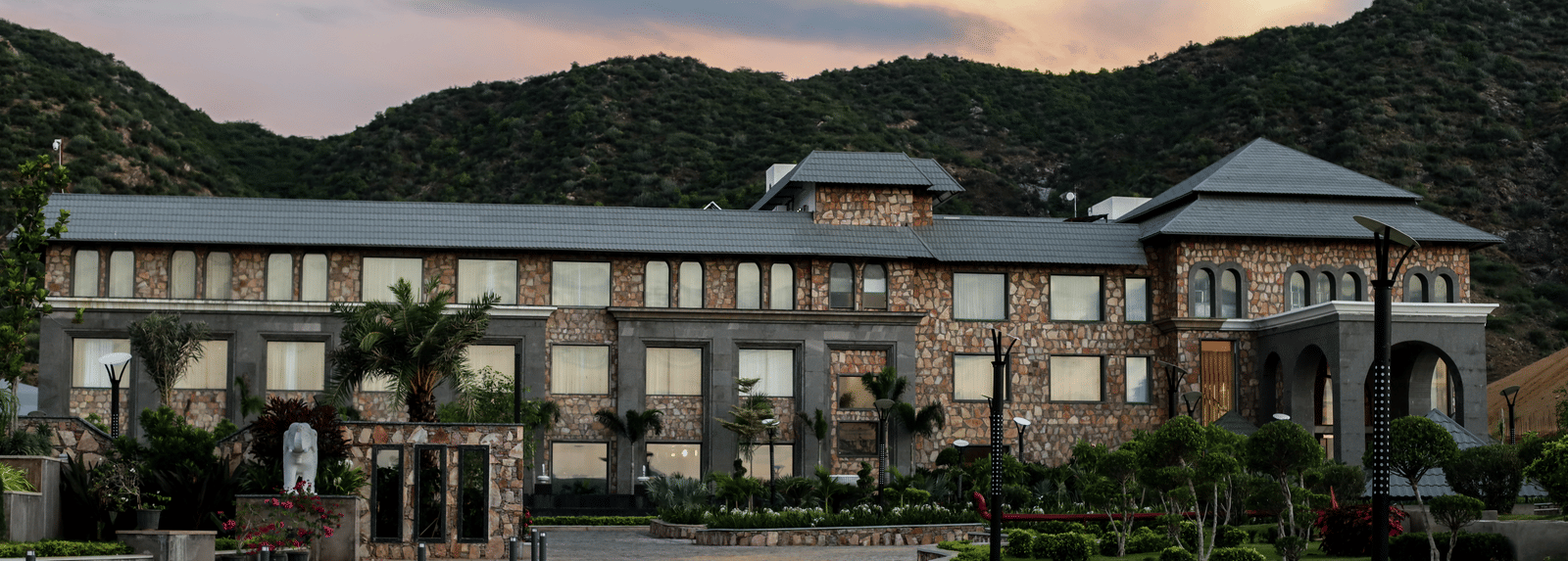 A different angle of the main resort building, with the driveway in the foreground and a warm, sunset-coloured sky.