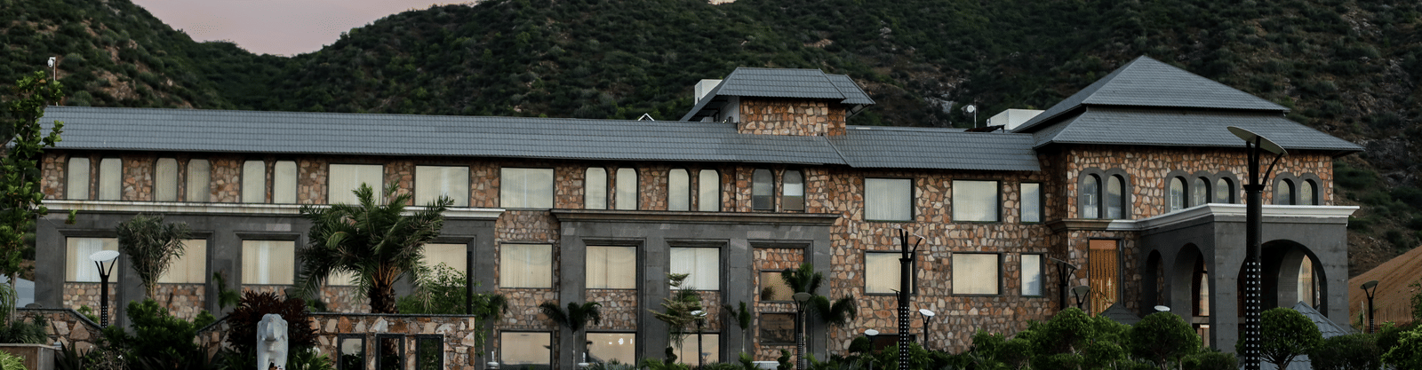 A different angle of the main resort building, with the driveway in the foreground and a warm, sunset-coloured sky.