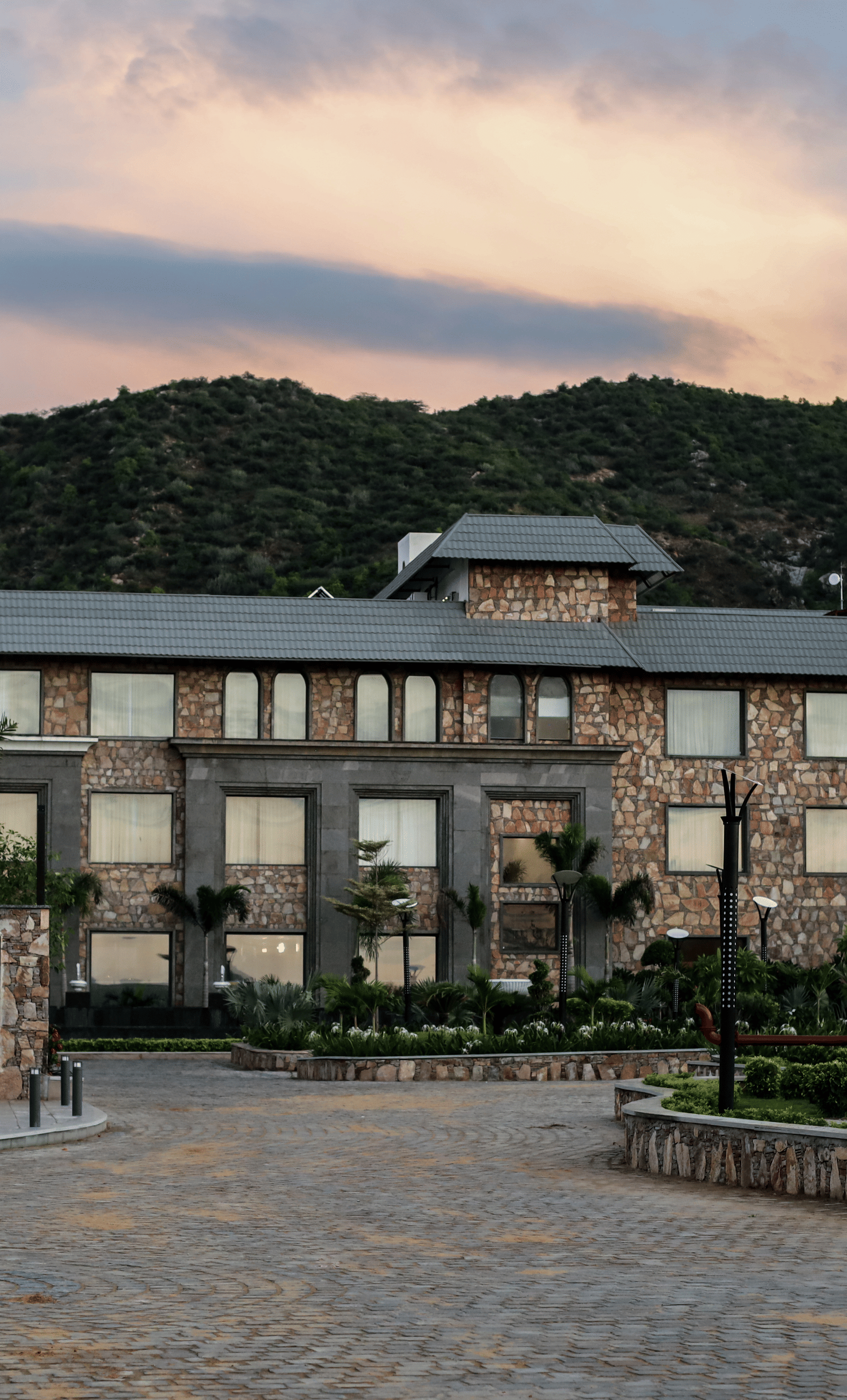 A different angle of the main resort building, with the driveway in the foreground and a warm, sunset-coloured sky.