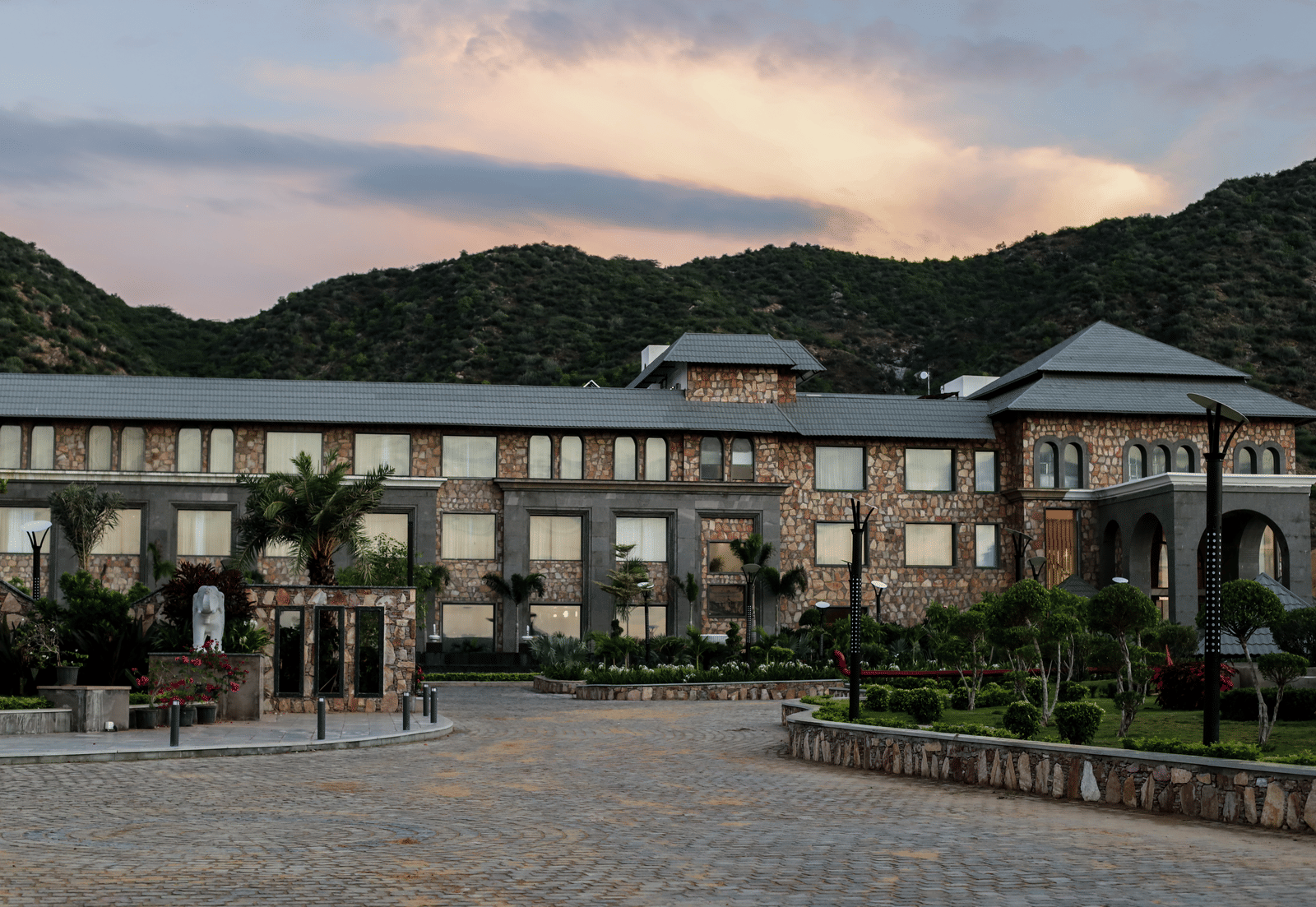 A different angle of the main resort building, with the driveway in the foreground and a warm, sunset-coloured sky.