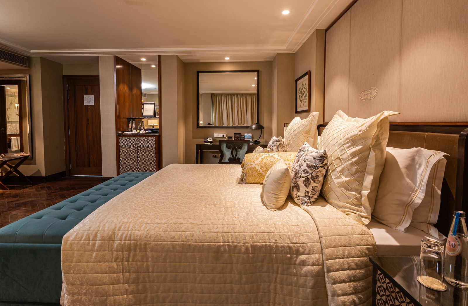 Side view of the king-size bed in the Cabana Room, with a work desk and minibar at the far end - The Claridges New Delhi