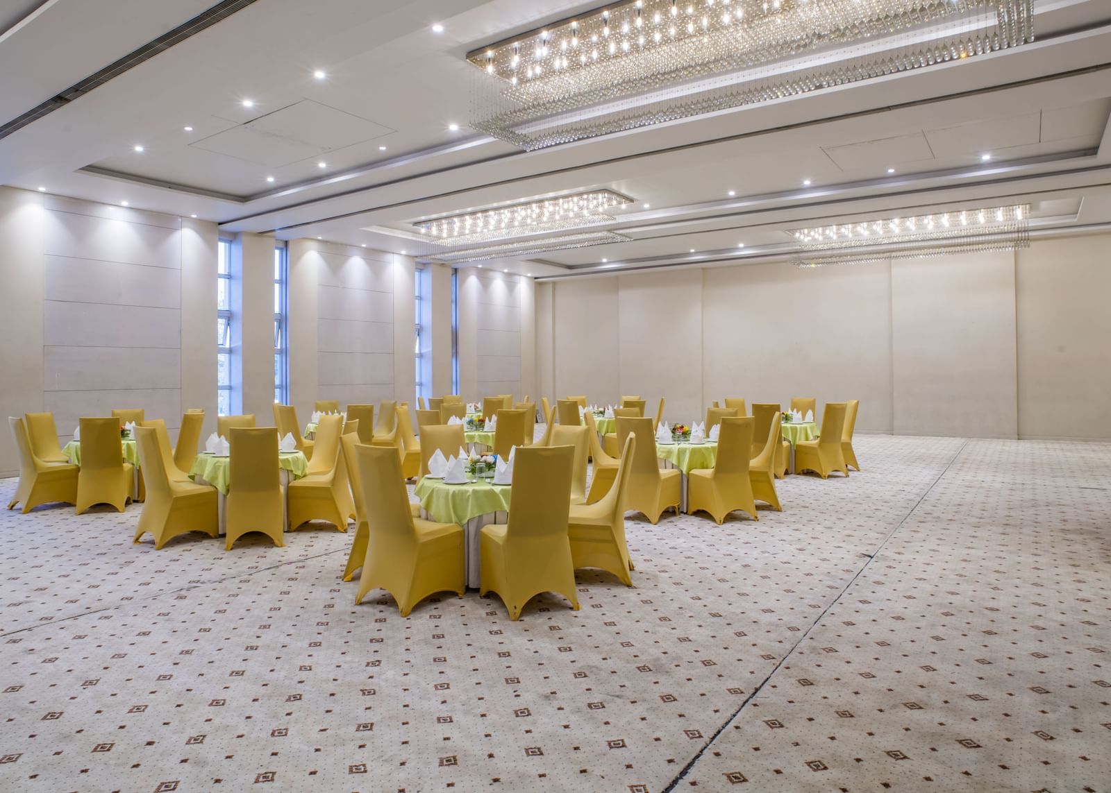 Another view of the large meeting room at The Citi Residenci Hotel, Asansol with golden chairs and textured flooring.