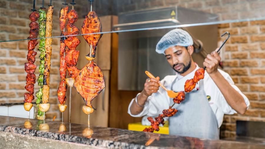 A chef tending to food cooking on a grill at The Citi Residenci Hotel, Durgapur.