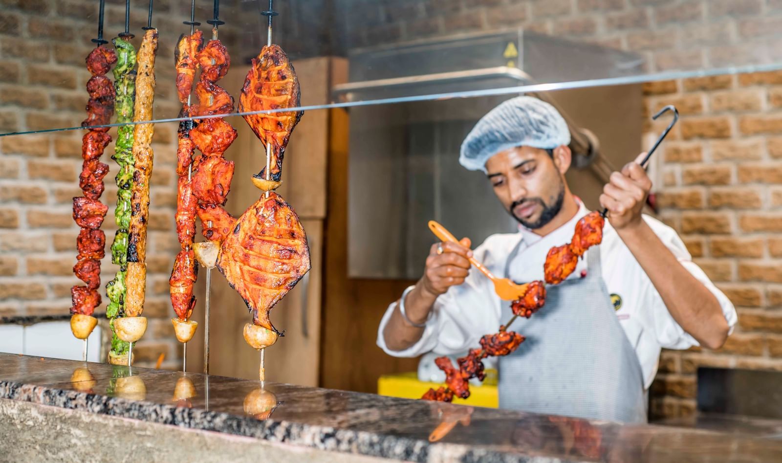 A chef tending to food cooking on a grill at The Citi Residenci Hotel, Durgapur.