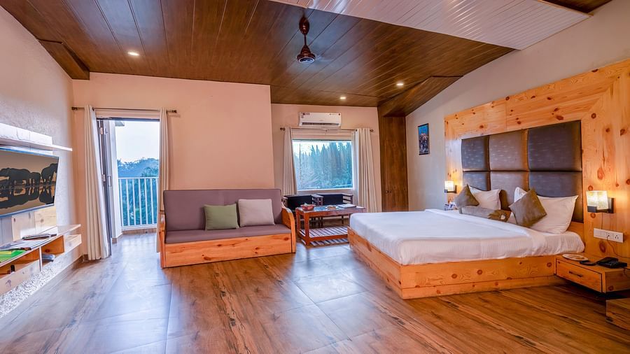 Spacious bedroom with wooden flooring at The Tattwaa Corbett Spa & Resort.