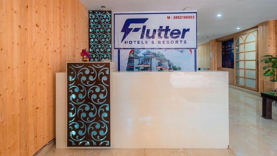 Reception desk at Flutter Hotels and Resorts with wooden walls and potted plants on the side.