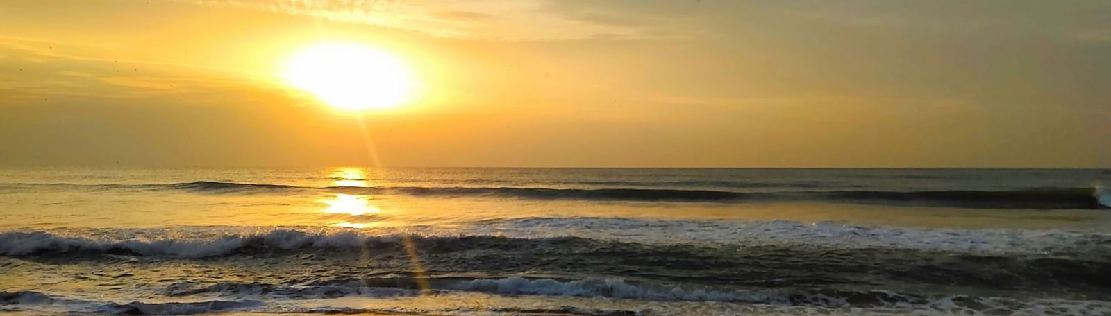 Golden sunset over a serene beach with calm waves | Mahabalipuram Resorts Near Beach