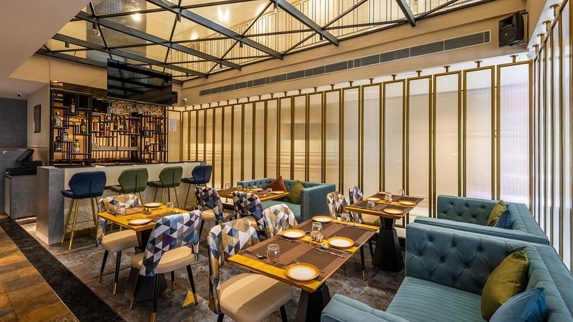 A wide view of the restaurant with furniture and a huge glass window  | Renest Calangute, Goa