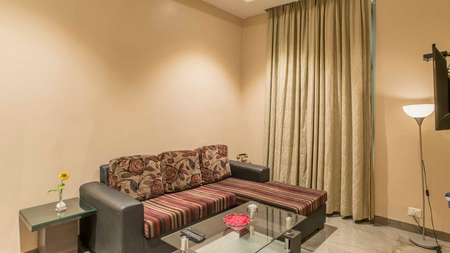 A cosy hotel living area features a sectional sofa, glass coffee table, and warm lighting | The Citi Residenci Hotel Durgapur