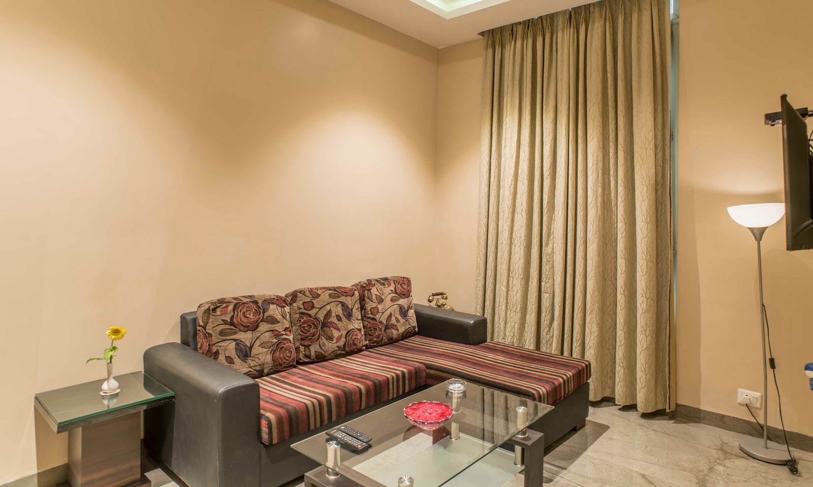 A cosy hotel living area features a sectional sofa, glass coffee table, and warm lighting | The Citi Residenci Hotel Durgapur