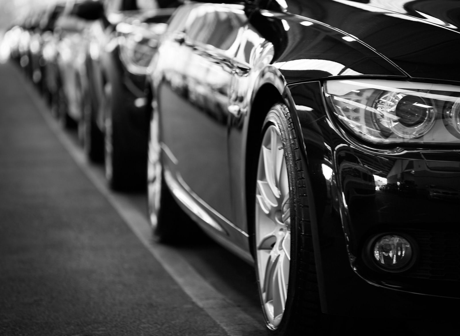 A b/w image of cars parked behind one another.