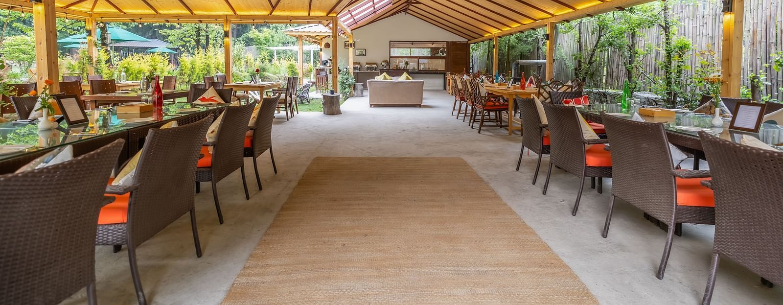 An open dining area with lavish wooden interiors, atttic style roof, wooden chairs and table at Bedzzz Xclusiv Baikunth, Manali