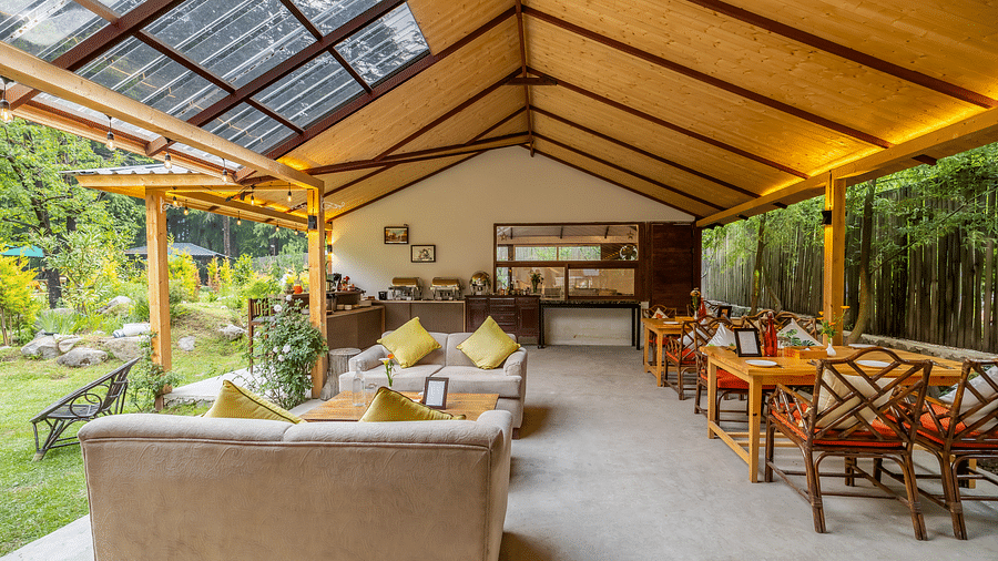 An open dining area with lavish wooden interiors, atttic style roof, wooden chairs and table at Bedzzz Xclusiv Baikunth, Manali