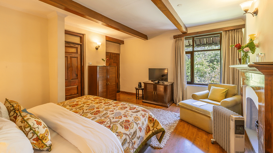 deluxe room with queen bed and TV and a sofa at Bedzz Xclusiv Baikunth, Manali