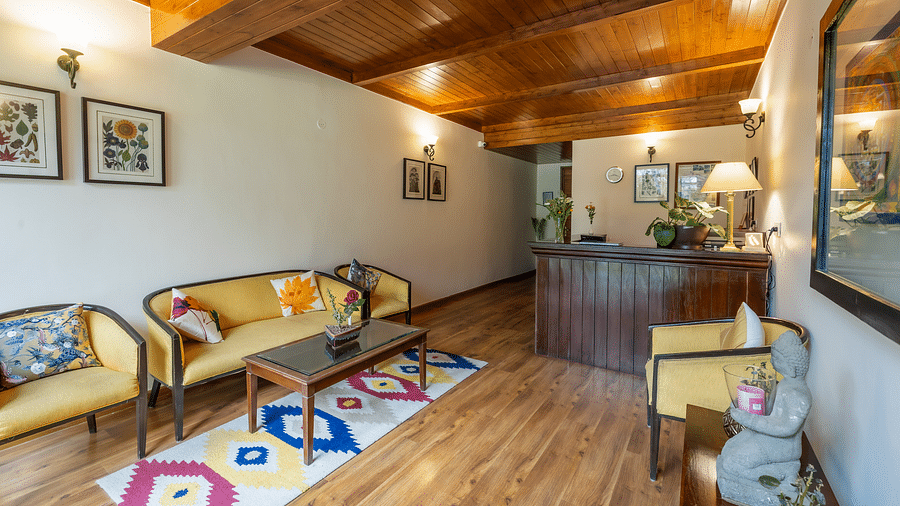 An image of a reception desk with seating arrangements and lavish wooden interiors at Bedzzz Xclusiv Baikunth, Manali