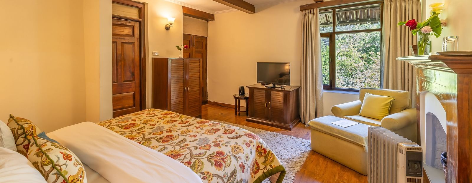 deluxe room with queen bed and TV and a sofa at Bedzz Xclusiv Baikunth, Manali