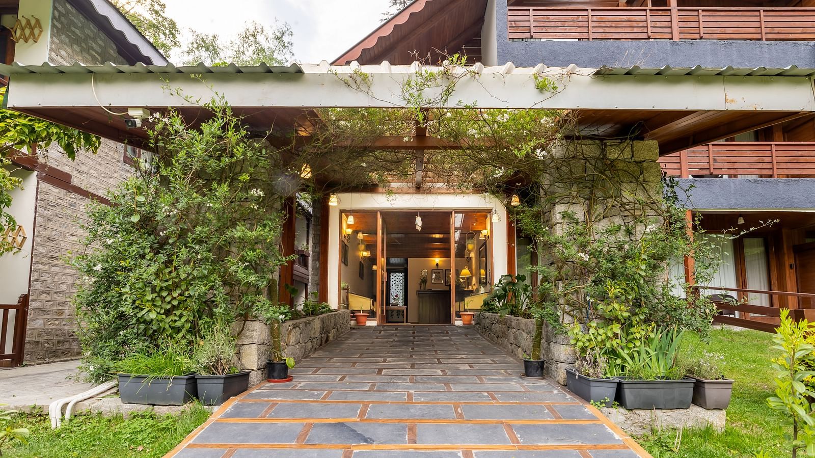 An image of the pavement leading to the Bedzzz Xclusiv Baikunth, Manali building which is surrounded by shrubs 