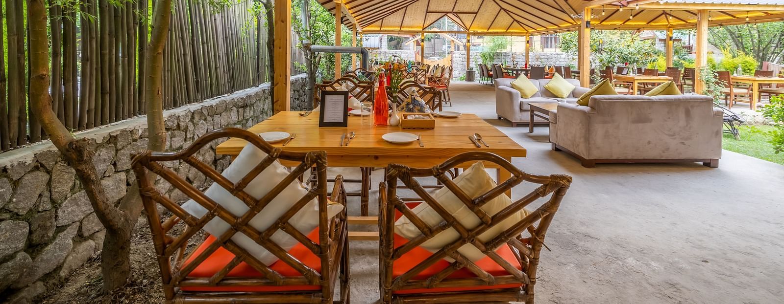 An open dining area with lavish wooden interiors, atttic style roof, wooden chairs and table at Bedzzz Xclusiv Baikunth, Manali