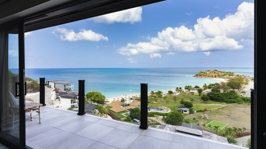 A private terrace overlooking the swimming pool, landscaped grounds, coastline, and sea at Suite 35, Tamarind Hills Resort and Villas.
