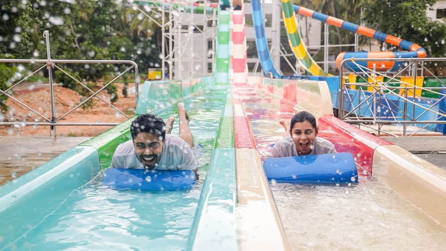 Two people joyfully sliding down a colorful water slide on mats at Black Thunder Water Theme Park.