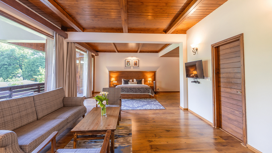 the xclusive room with lavish wooden interiors with a sofa and queen bed at Bedzzz Xclusiv Baikunth