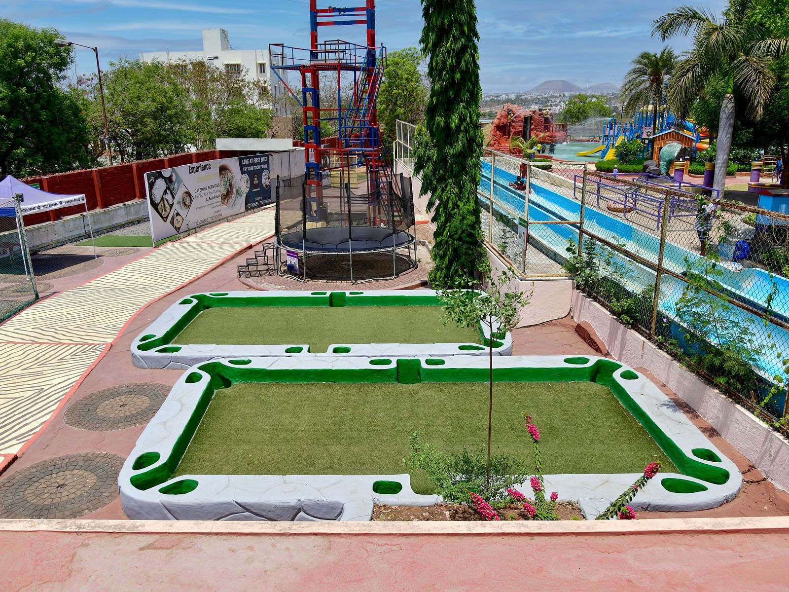 Outdoor mini golf course with lush greenery and blue ocean in the background |  Diamond Parks, Pune