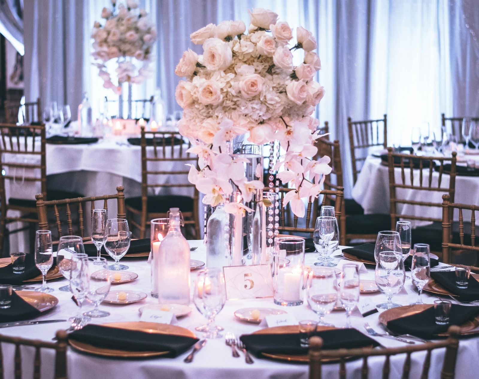 A decorated banquet hall with elegantly set dining tables and floral centrepieces.