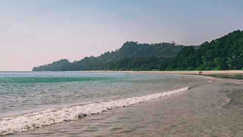 A view of Radhanagar Beach with a mountain in the background, it is one of the perfect places for Weekend Getaways from Chennai.