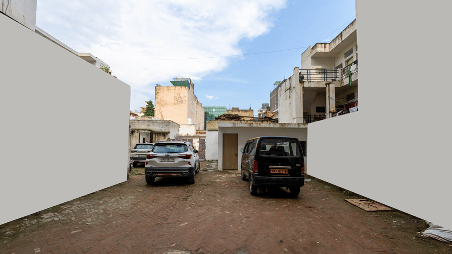 2 cars parked in an open lot between 2 walls under a bright blue sky at Hotel Corporate Suites