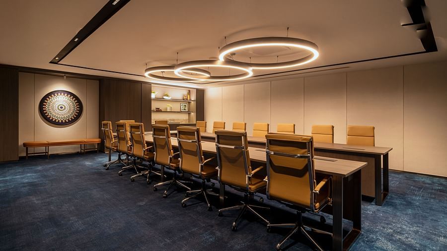 A corner angle of the meeting room at The Residency Towers Chennai, showcasing the table, chairs, and circular lighting.