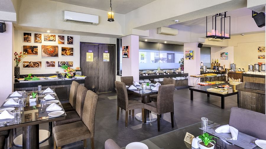 A restaurant in Candolim with wall arts, dining tables, and warm lighting - Golden Tulip, Candolim, Goa